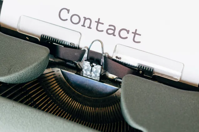 Bilden visar en skrivmaskin med ett pappersark som det står contact på