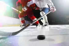 Två ishockeyspelare försöker vinna pucken, fotografi. Foto: iStock/gilaxia